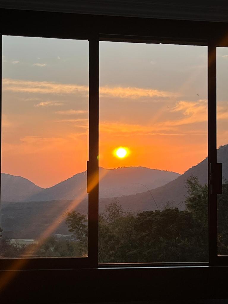 View of a sunset over mountains framed by a large window.