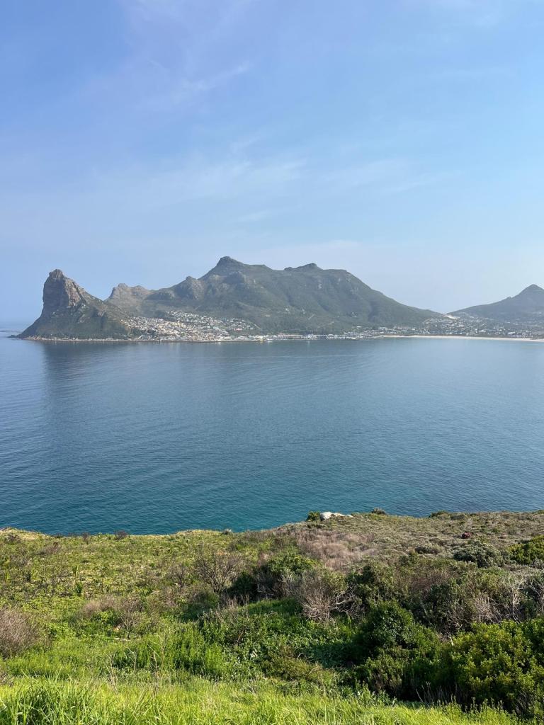 Scenic view of mountains and coastline with calm water in the foreground under a clear blue sky.